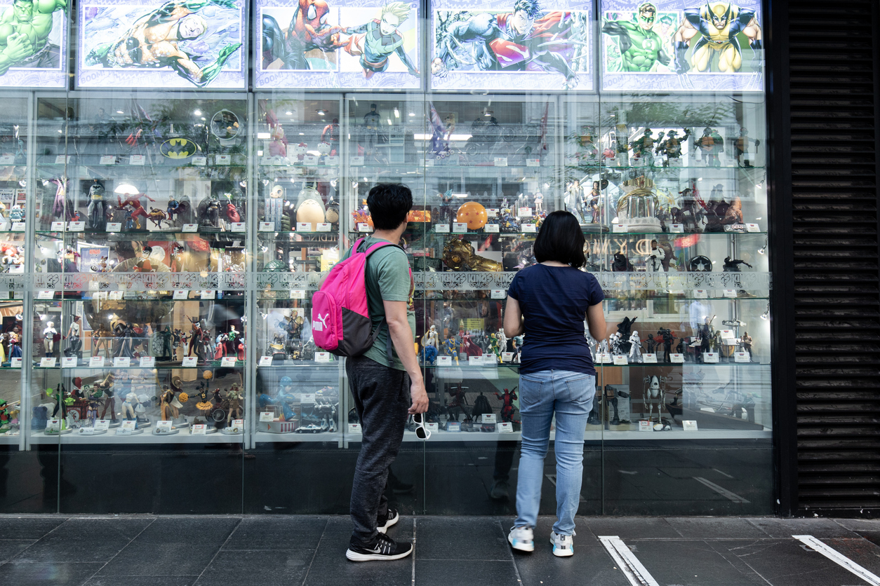 Two people looking at figurines in front of the shop
